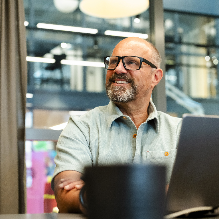 Person at laptop in a modern office, looking away; AI in recruitment concept showing candidate screening and remote hiring